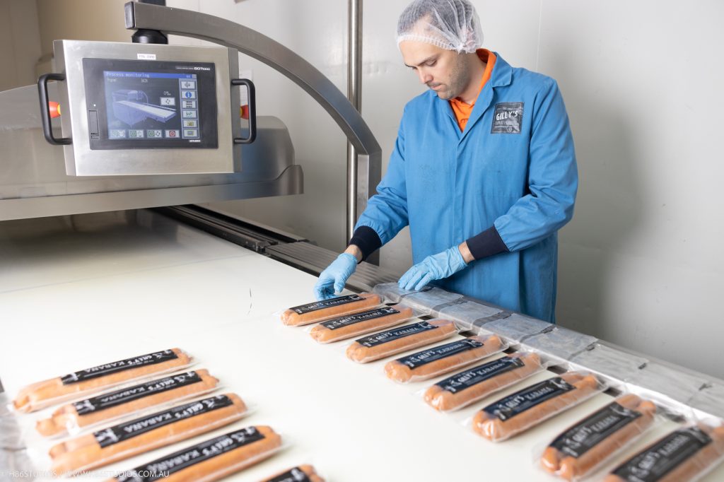 A factory worker prepping sausages to be vacuum packed.